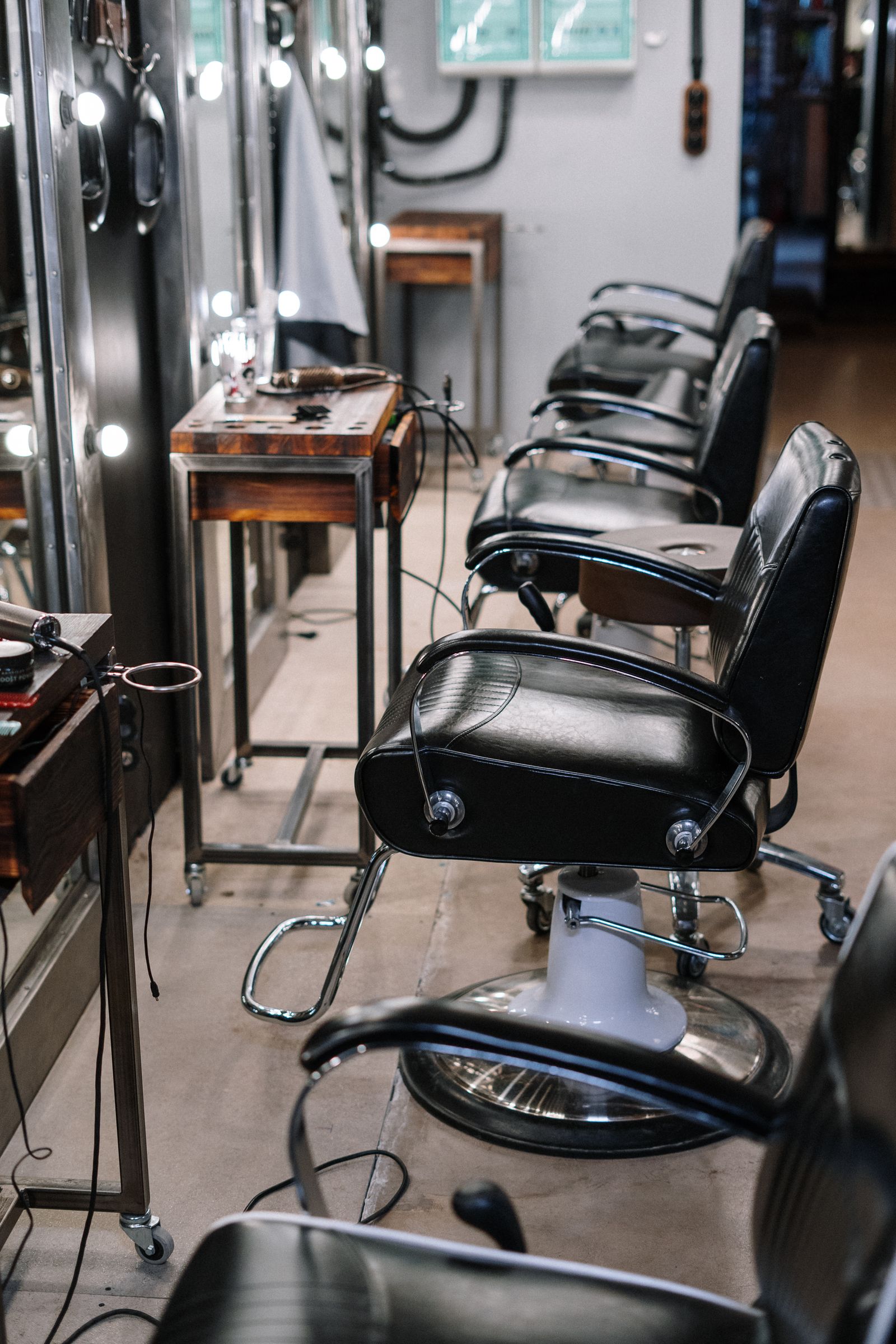 Sillón de barbería de cuero negro frente a un espejo