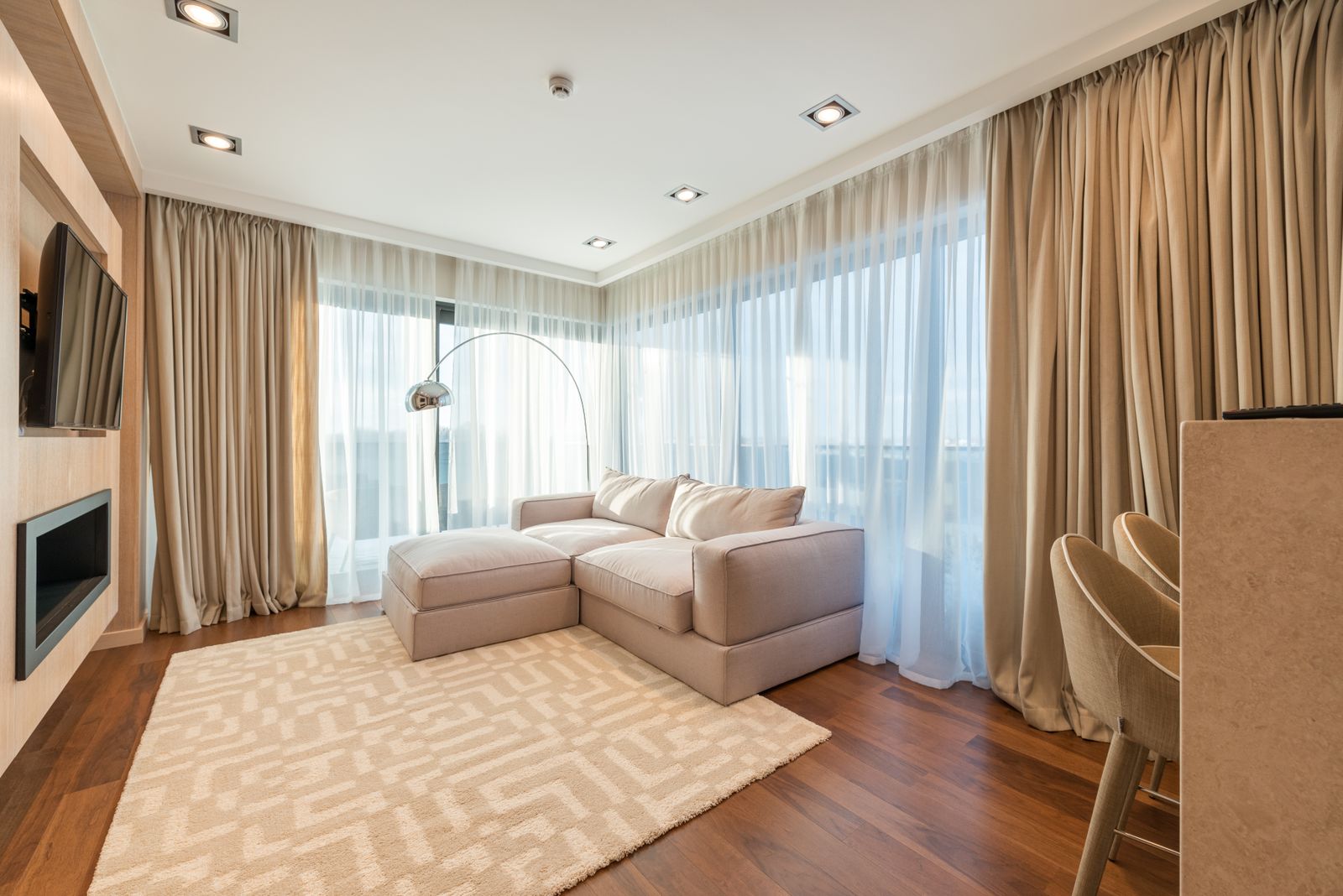 Salón luminoso con sofá, grandes ventanas y comedor integrado