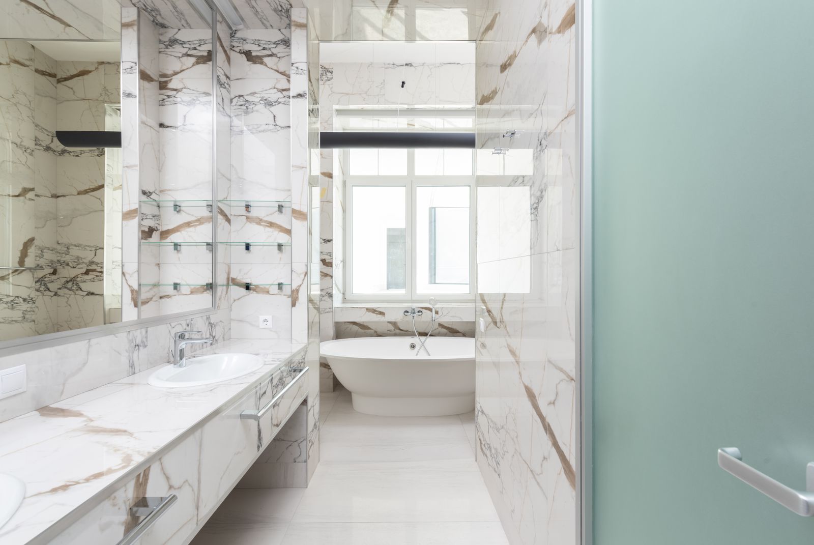 Baño contemporáneo con revestimientos de mármol y bañera