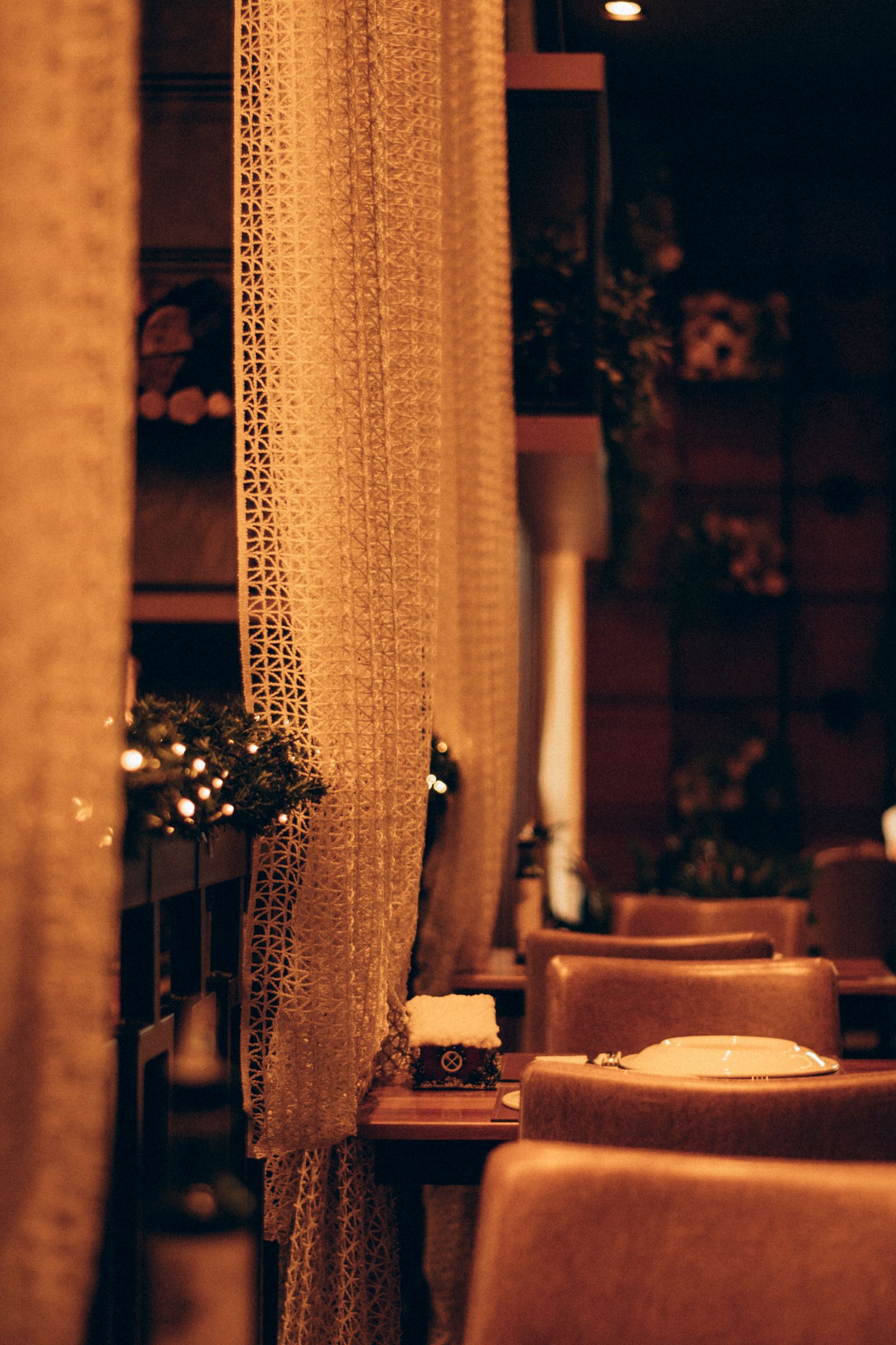 Restaurante con mesas, cortinas e iluminación cálida